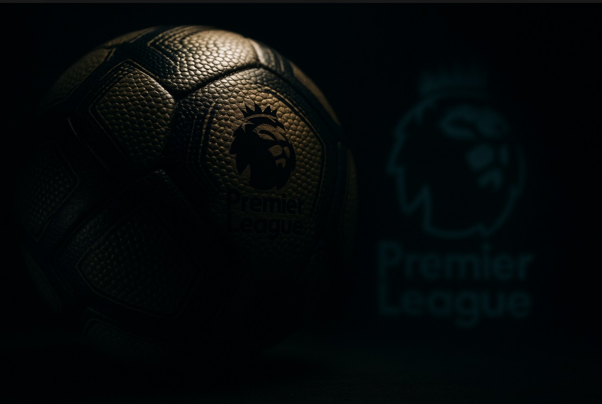 Dramatiskt belyst närbild av en fotboll med Premier League-loggan synlig i bakgrunden mot en mörk och stämningsfull bakgrund.